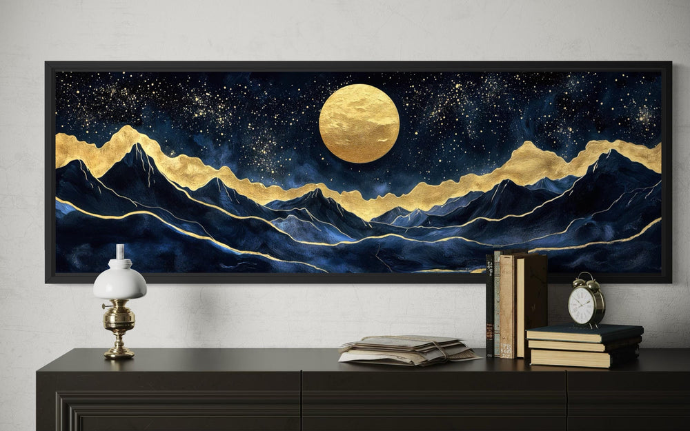 Panoramic canvas print of a gold moon over navy mountains with gold accents in a black frame.