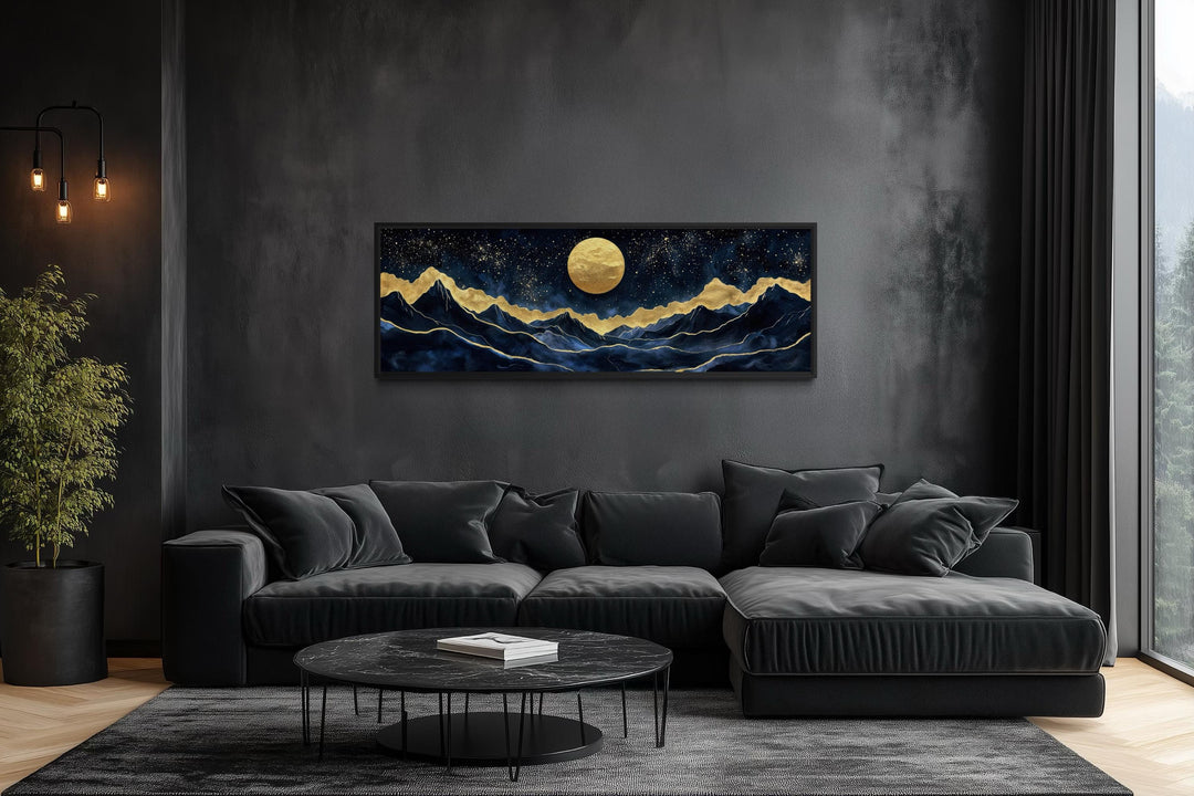 Panoramic canvas print of a gold moon over navy mountains in a modern black living room.