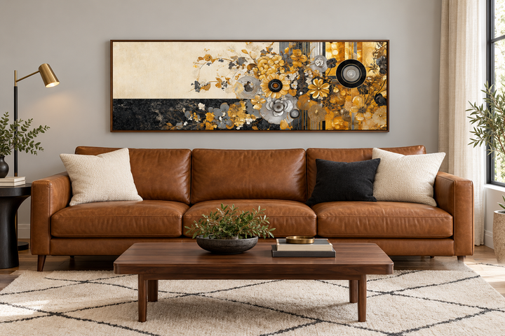 Gold, silver, and black floral abstract horizontal wall art in a walnut frame above a leather sofa.