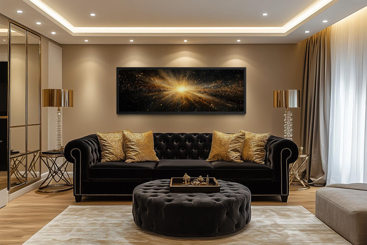 Horizontal black and gold starburst wall art displayed above a black velvet sofa in a modern room.