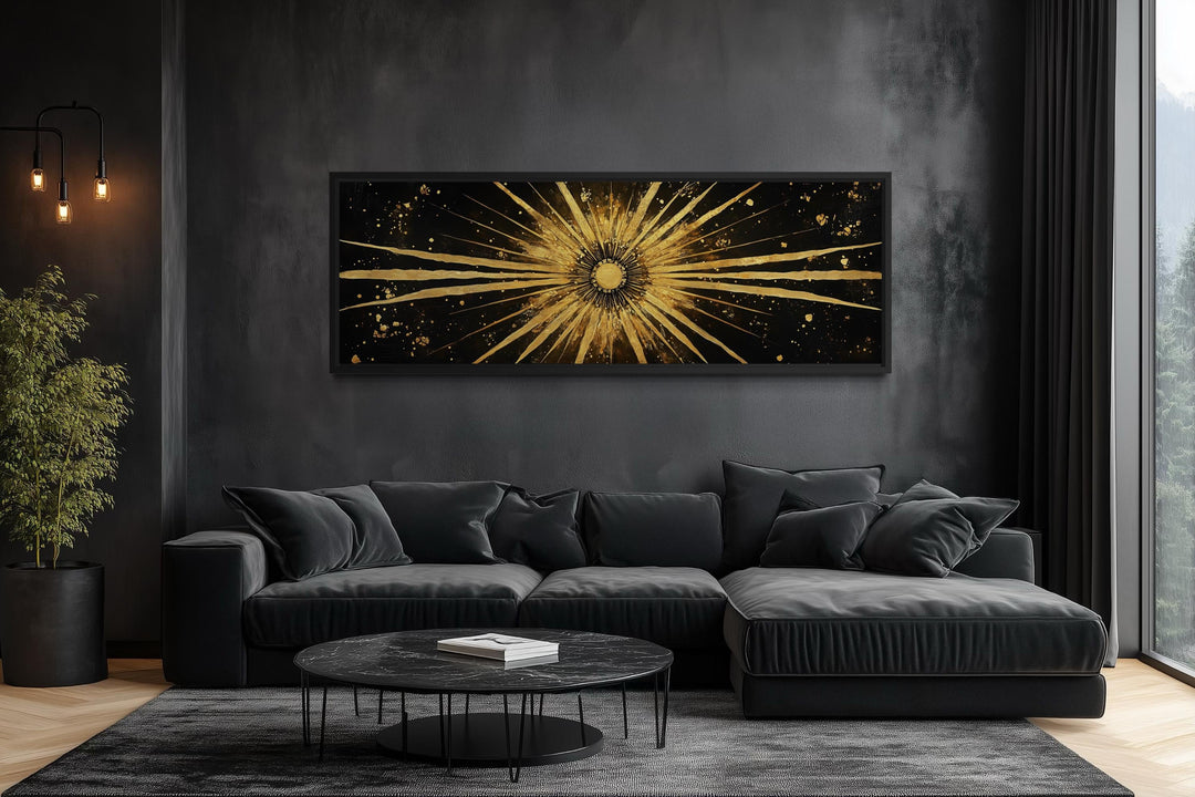 Long horizontal black and gold sunburst abstract painting above a dark grey sofa in a modern room.