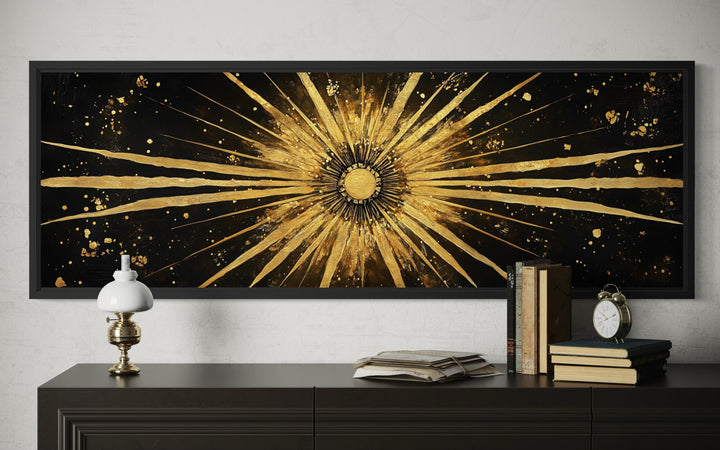 Horizontal black and gold sunburst abstract canvas painting above a dark sideboard.
