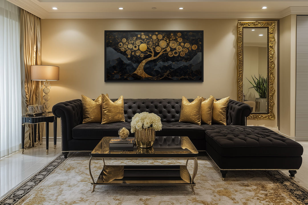 Gold Tree of Life wall art on a black background hanging above a black tufted sofa in a living room.