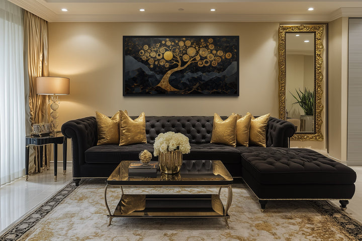 Gold Tree of Life wall art on a black background hanging above a black tufted sofa in a living room.
