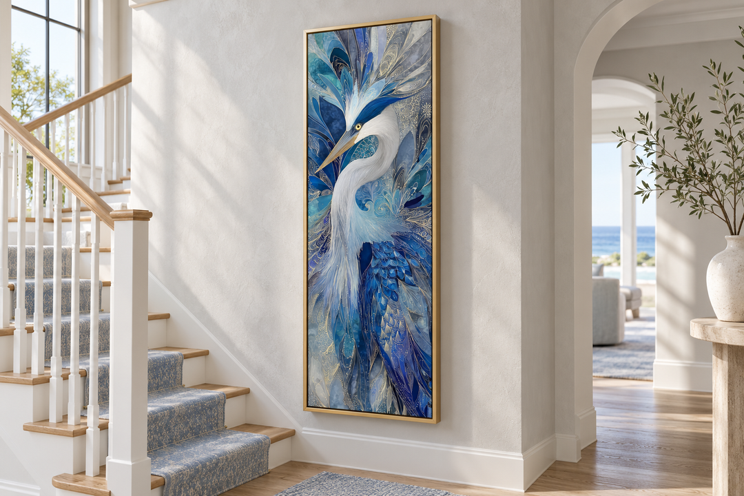 Vertical canvas print of an elegant blue heron in a gold frame, hanging on a white stairway wall.