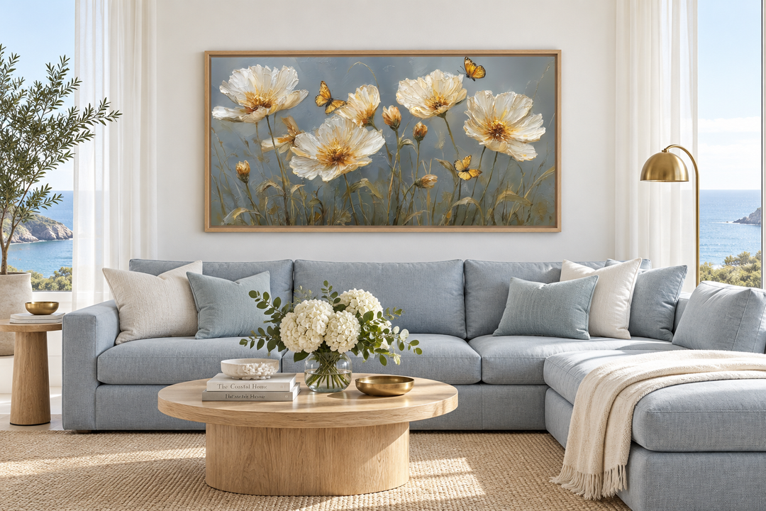 Framed horizontal wall art of golden flowers and butterflies above a blue sectional sofa.