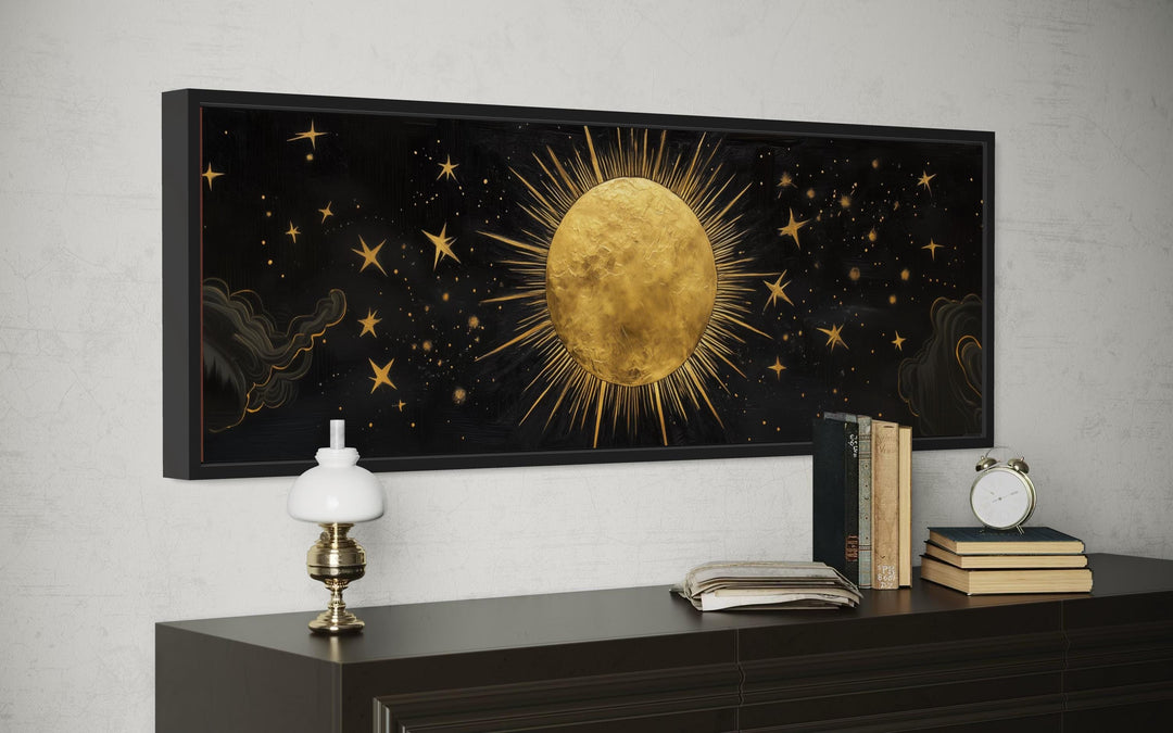 Golden sun and stars on a black horizontal canvas wall art above a dark wood dresser.