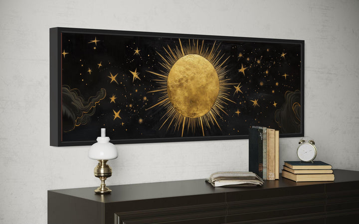Golden sun and stars on a black horizontal canvas wall art above a dark wood dresser.