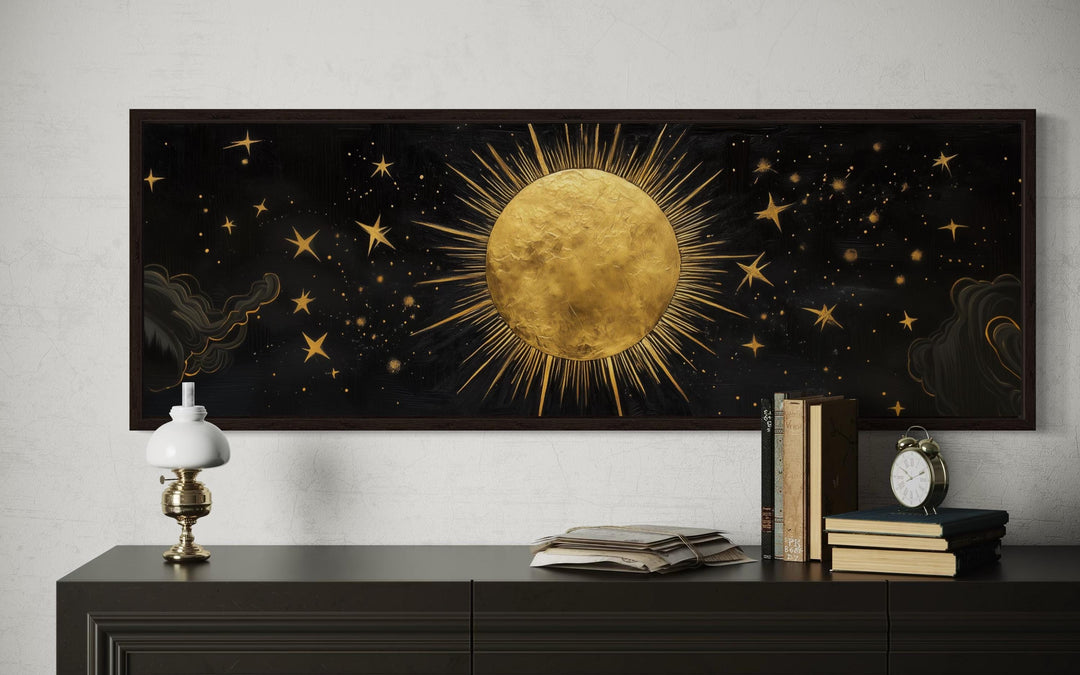 Golden sun and stars on a black horizontal canvas wall art above a dark wood console table.