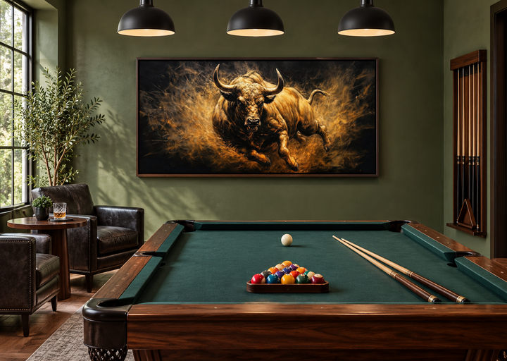 Extra large framed canvas painting of a charging bull in gold and black above a pool table.