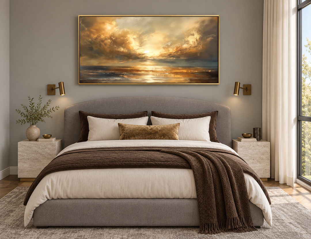 Framed golden sunset ocean seascape wall art hanging above a gray upholstered bed in a bedroom.