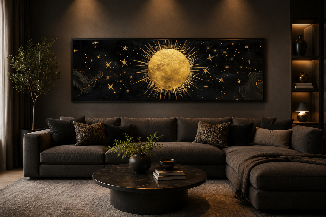 Golden sun and stars celestial painting on a long horizontal canvas above a dark grey sofa.