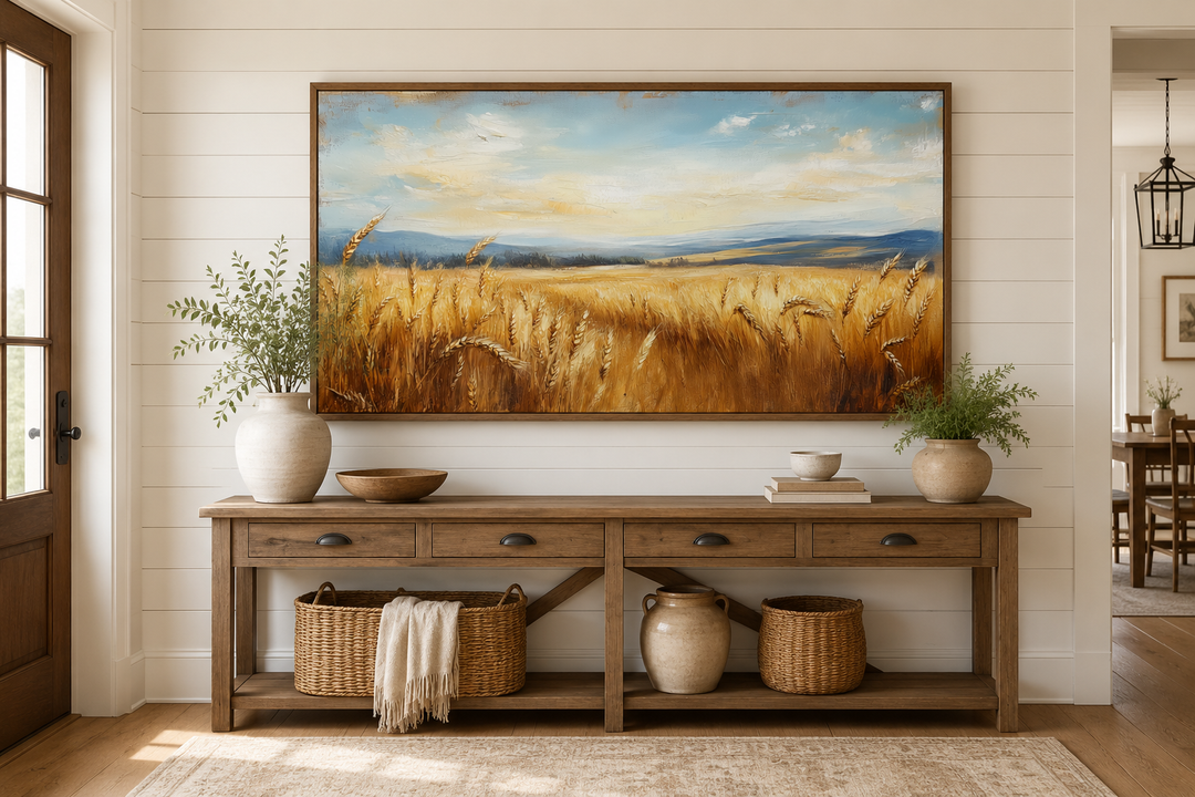 Golden wheat field landscape painting in a wood frame above a rustic console table.