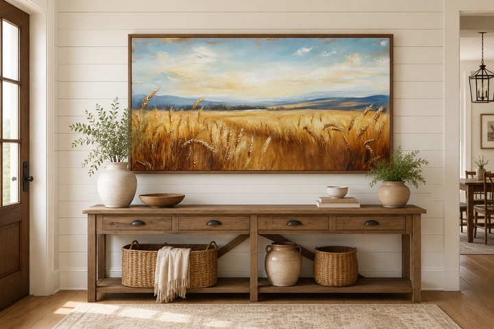 Golden wheat field landscape painting in a wood frame above a rustic console table.