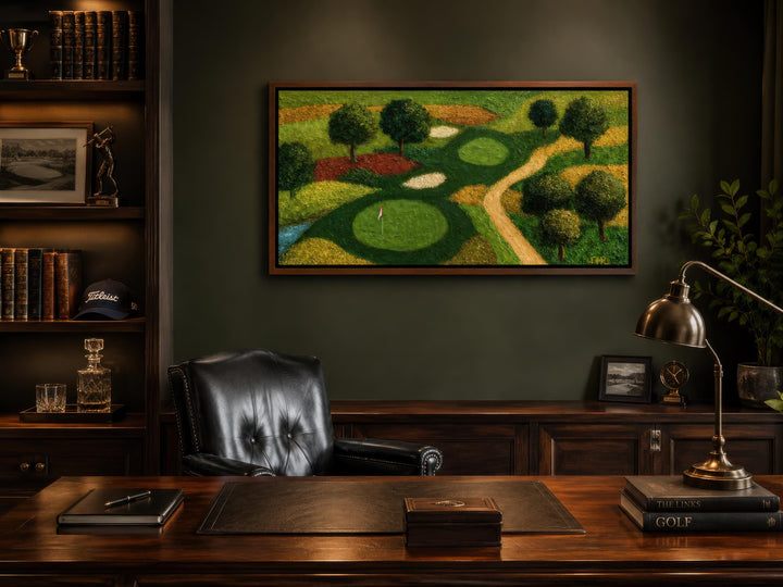 Aerial view golf course painting in a dark wood frame above a desk in a home office.