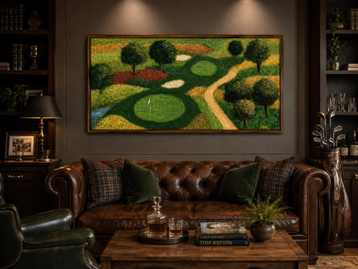 Aerial view golf course canvas painting above a leather sofa in a dark-toned study or man cave.