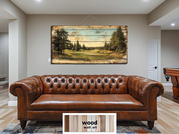 A panoramic golf course scene printed on distressed wood planks hangs above a brown leather sofa.