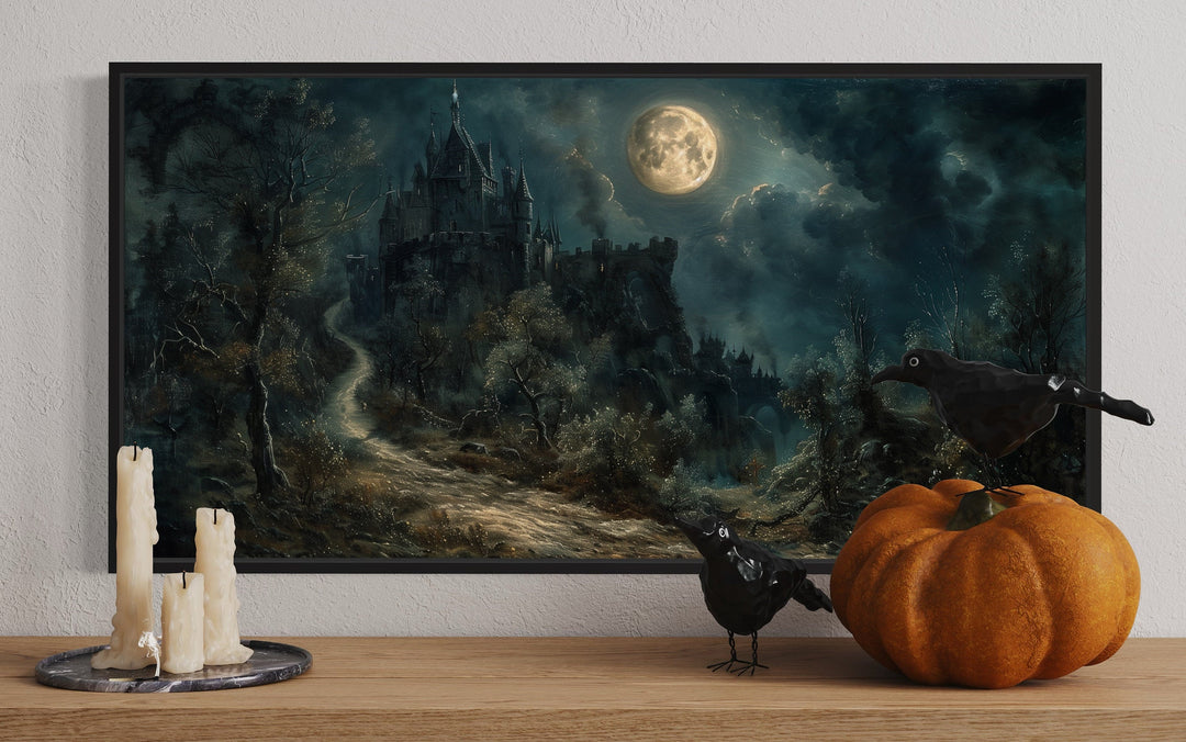 Framed gothic artwork of a haunted castle under a full moon with Halloween decor on a shelf.