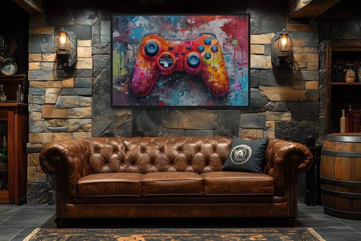 Framed canvas wall art featuring a vibrant graffiti-style game controller above a leather sofa.
