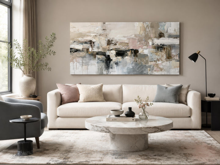 Horizontal abstract canvas print with gray, beige, and blush brushstrokes above a white sofa.