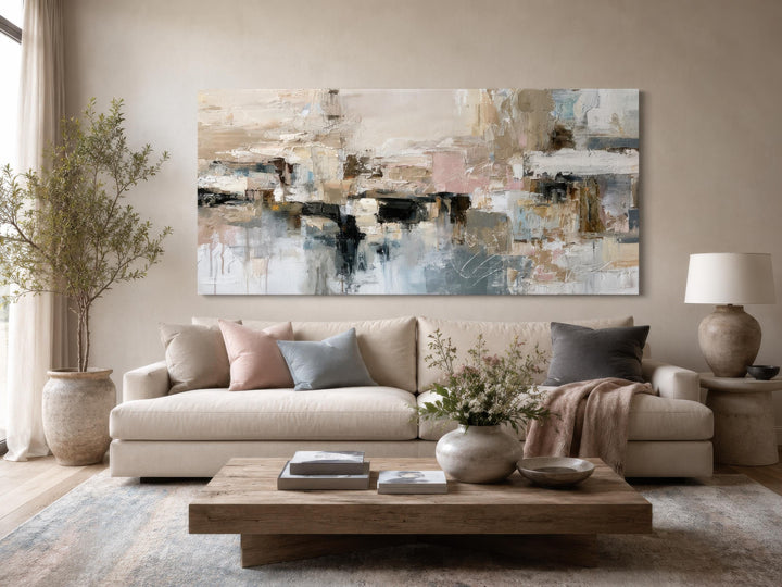Horizontal abstract canvas print with gray, beige, and blush brushstrokes above a neutral sofa.
