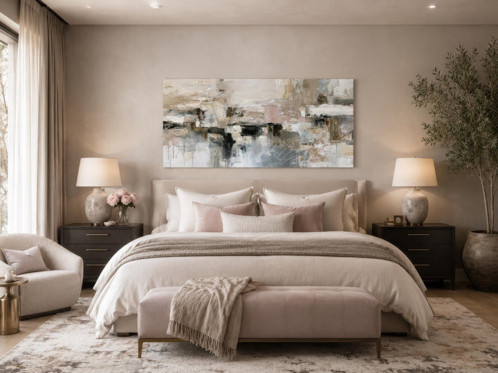 Horizontal abstract canvas print with gray, beige, and blush tones above a bed in a neutral room.