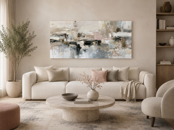Horizontal abstract canvas print with gray, beige, and blush brushstrokes above a neutral sofa.