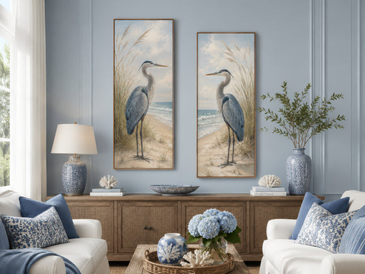 a serene living room with two large paintings of blue herons hanging on the wall, a wooden cabinet, a sofa, a coffee table, and decorative elements such as a vase of flowers and a potted plant.
