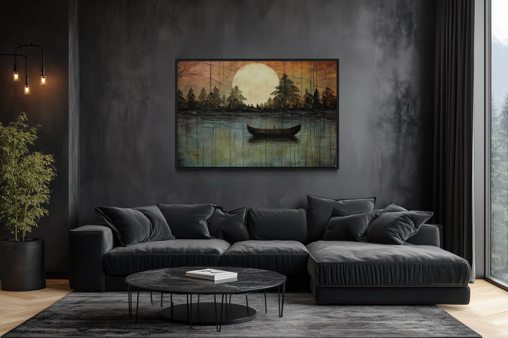 Framed canvas wall art of a boat on a moonlit lake above a black sofa in a dark modern living room.