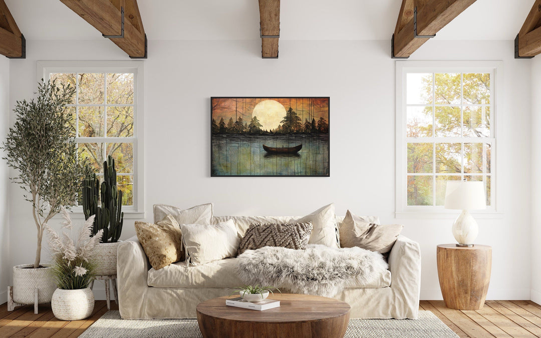 Framed canvas wall art of a moonlit lake with a boat, hanging above a sofa in a rustic living room.