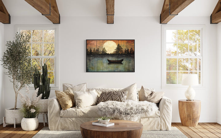 Framed canvas wall art of a moonlit lake with a boat, hanging above a sofa in a rustic living room.