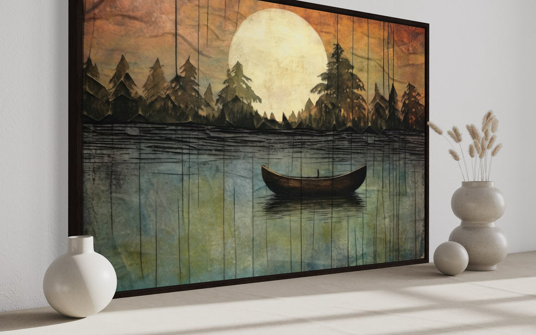Framed canvas wall art of a boat on a lake under a full moon, styled for cabin or cottage decor.
