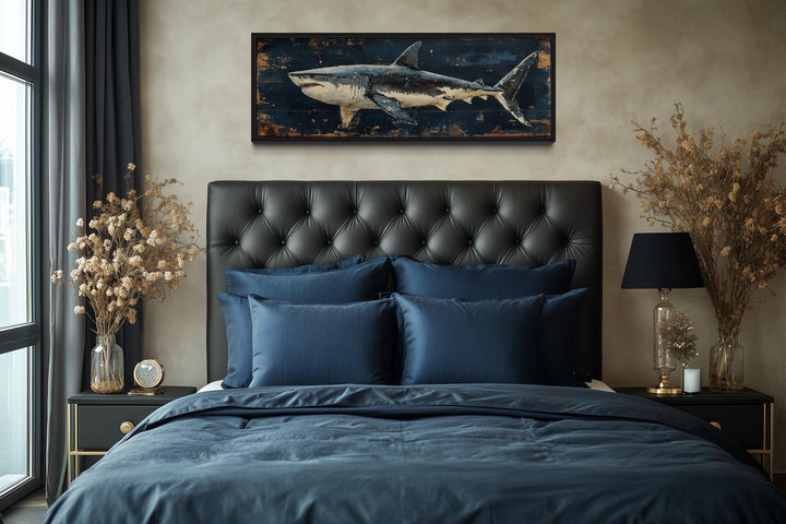 Great white shark horizontal canvas wall art above a black tufted headboard in a masculine bedroom.