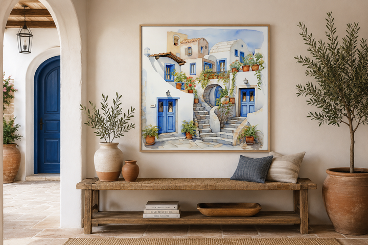 Framed watercolor canvas art of Santorini Greek houses above a wooden bench in a Mediterranean room.