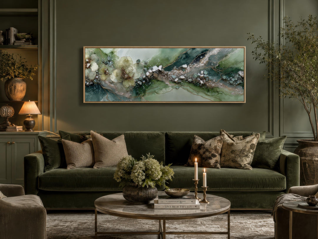 Long horizontal sage green geode canvas print with floral accents above a green velvet sofa.