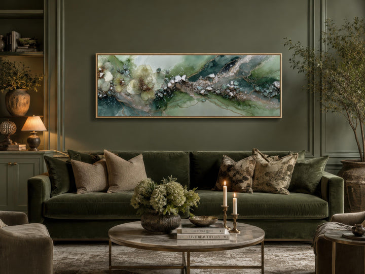 Long horizontal sage green geode canvas print with floral accents above a green velvet sofa.