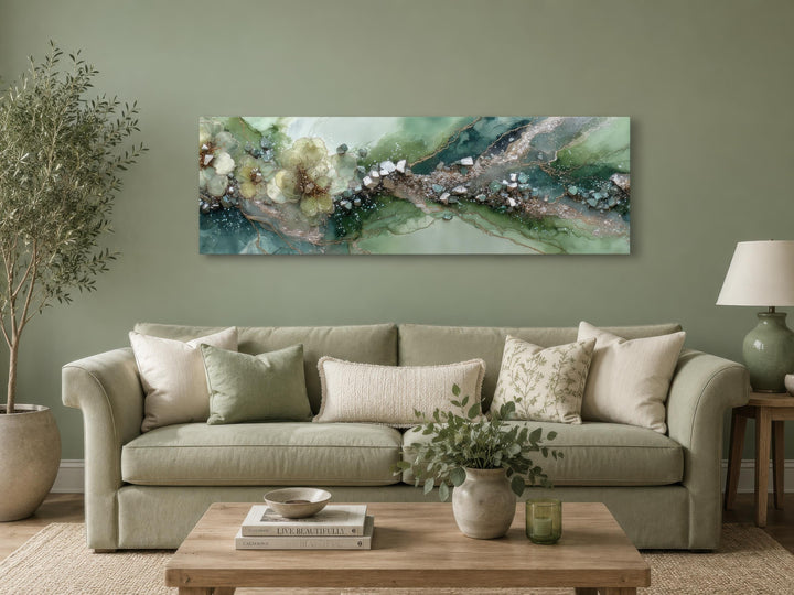 Long horizontal sage green geode canvas print with floral accents above a sofa in a living room.