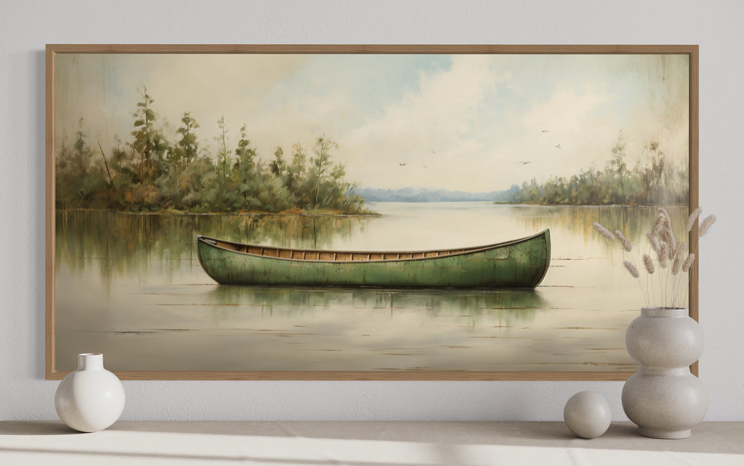 Framed canvas painting of a green canoe on a calm lake with rustic wood frame and nature scenery.