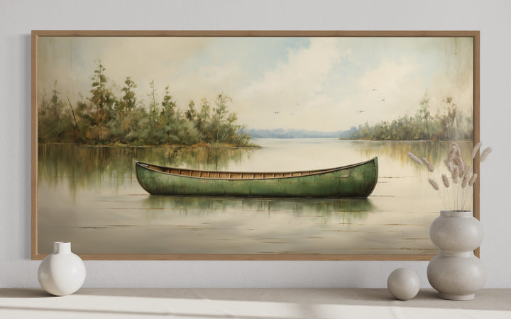 Framed canvas painting of a green canoe on a calm lake with rustic wood frame and nature scenery.