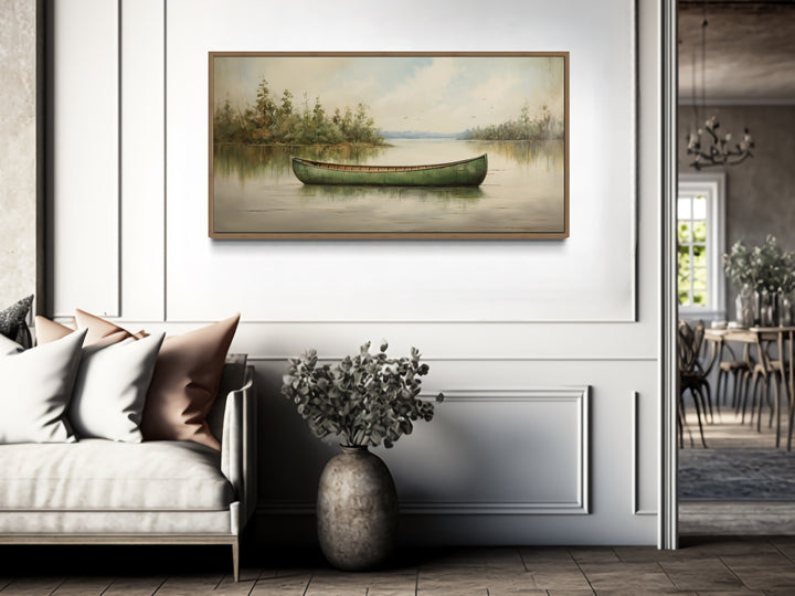 Framed canvas painting of a green canoe on a calm lake, styled in a rustic living room.
