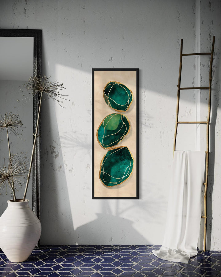 Vertical abstract canvas print featuring three emerald green stones with gold accents on a wall.