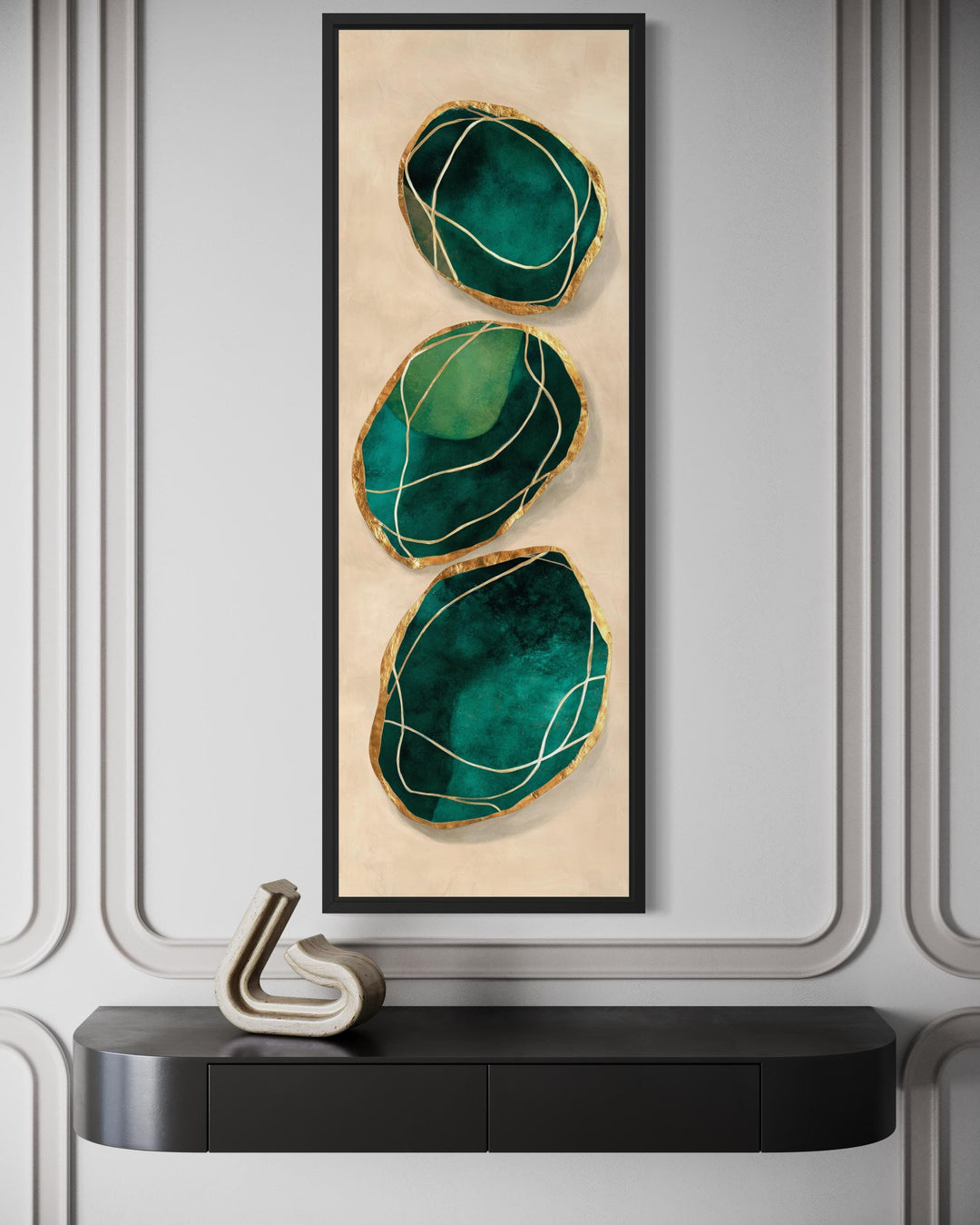 Vertical abstract wall art featuring three emerald green stones with gold accents in a black frame.