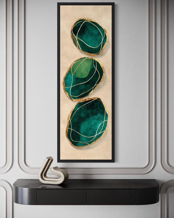 Vertical abstract wall art featuring three emerald green stones with gold accents in a black frame.