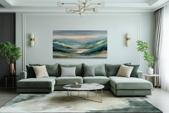Horizontal green, grey, and gold mountain landscape wall art centered above a modern green sofa.