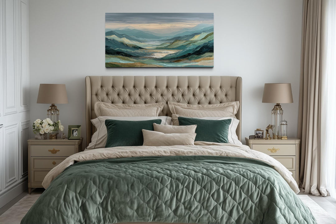 Horizontal mountain landscape wall art in green, grey, and gold tones hanging above a tufted bed.