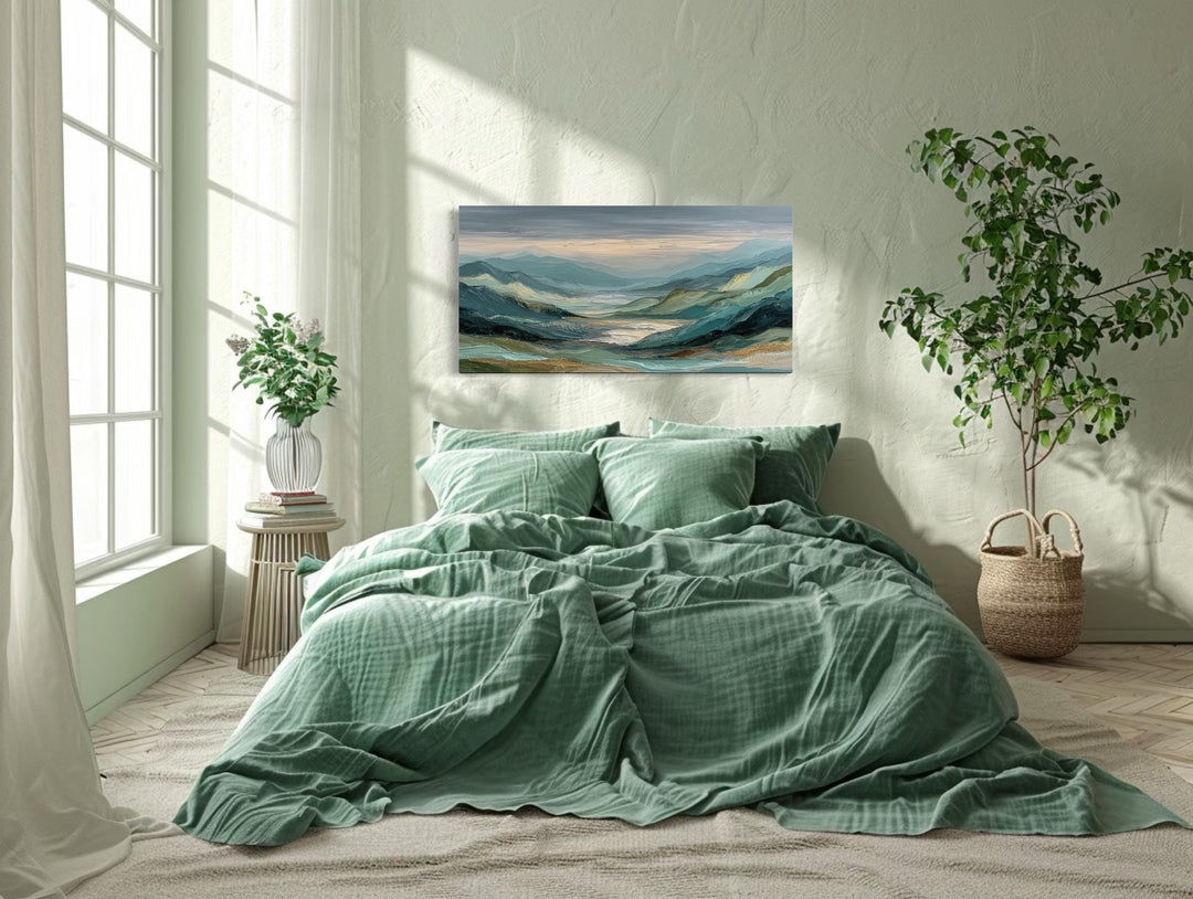 Horizontal wall art of a green, grey, and gold mountain landscape hanging above a bed.