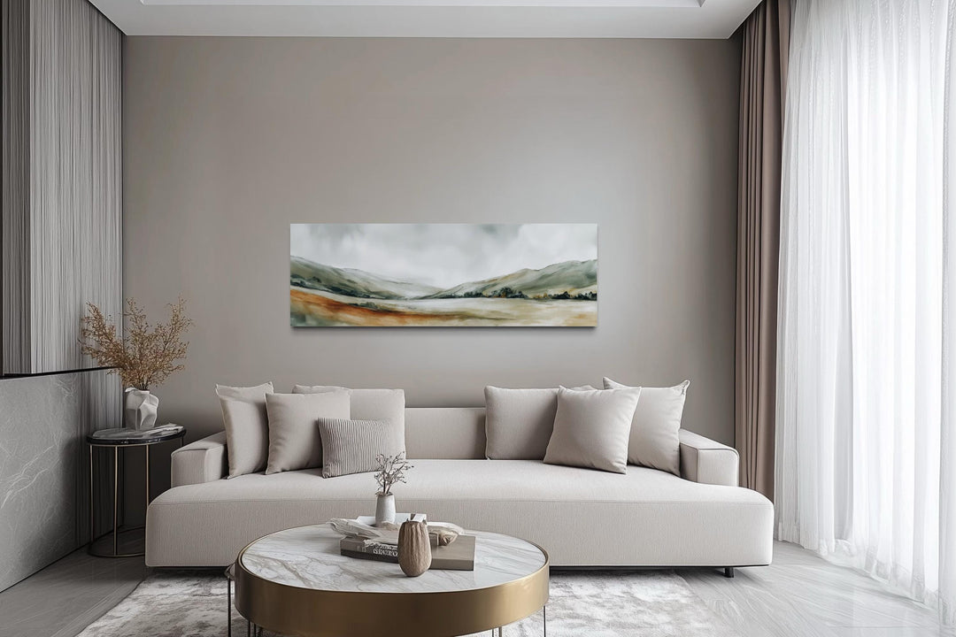 Panoramic green landscape canvas print with sage hills and misty sky above a neutral sofa.