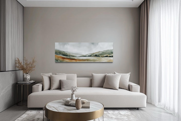 Panoramic green landscape canvas print with sage hills and misty sky above a neutral sofa.