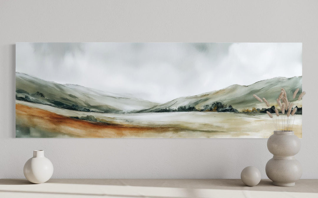 A panoramic canvas print of a minimalist green landscape hangs above neutral ceramic decor.