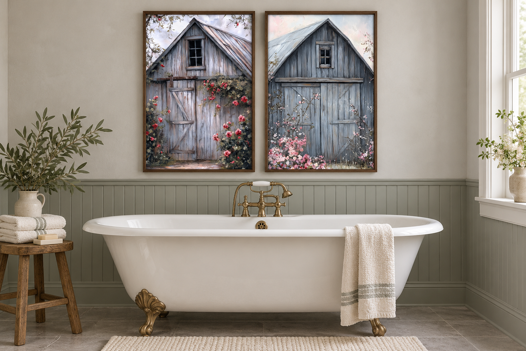 Two framed canvas paintings of rustic grey barn doors with pink flowers above a white clawfoot tub.